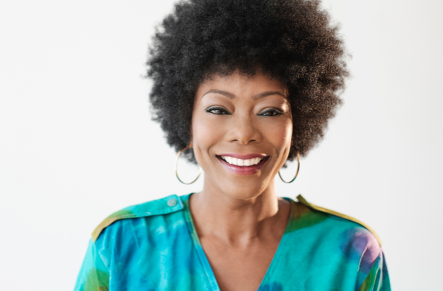 Smiling woman with hoop earrings and afro.